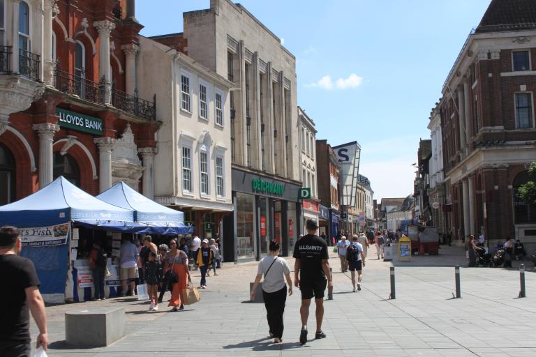 People walking by market stalls and town centre shops