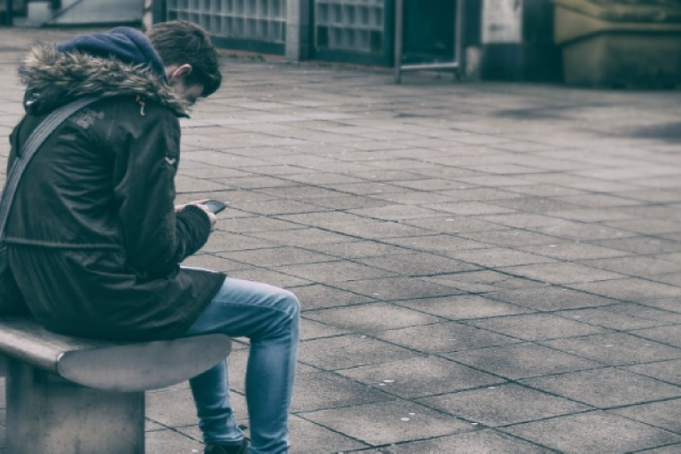 An image showing a young person sitting on a bench