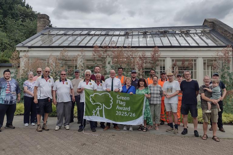 Group of people display Green Flag awarded to Holywells Park in Ipswich