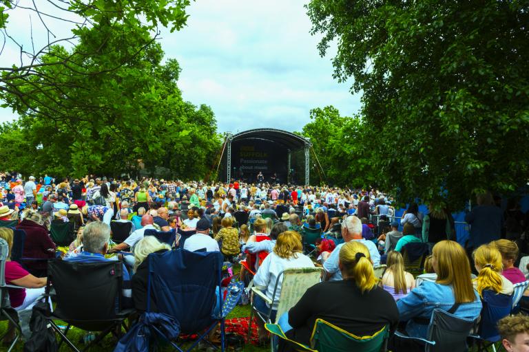 A crowd in front of an outdoor stage in a park