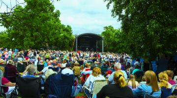 A crowd in front of an outdoor stage in a park