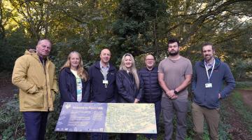 A group of seven people standing around a sign in a country park